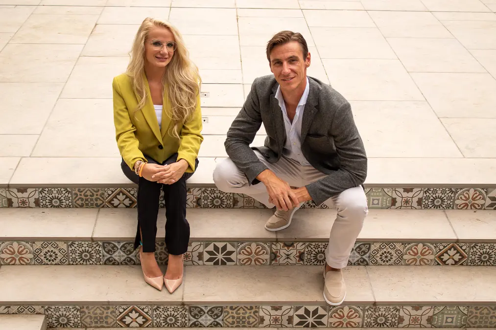 Darcie and Erwin, founders of Go Ahead HiRe, sitting on Mediterranean tiled steps - representing the cross-border European reach of the agency